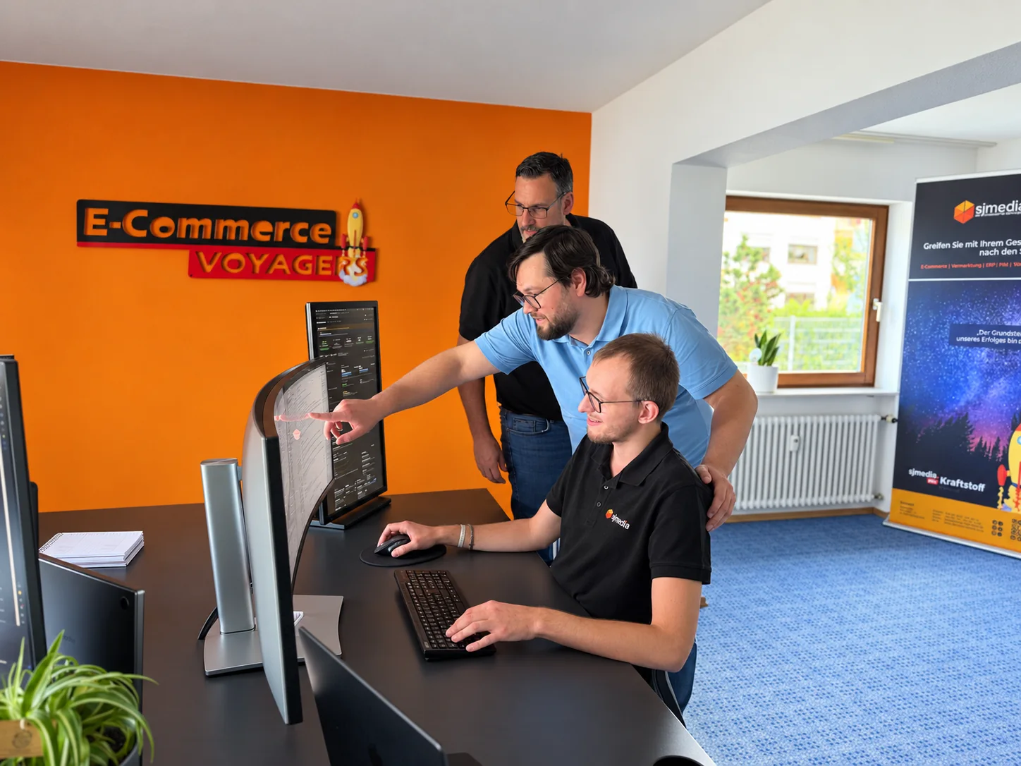Drei sjmedia-Mitarbeiter arbeiten gemeinsam an einem Onlineshop am Bildschirm