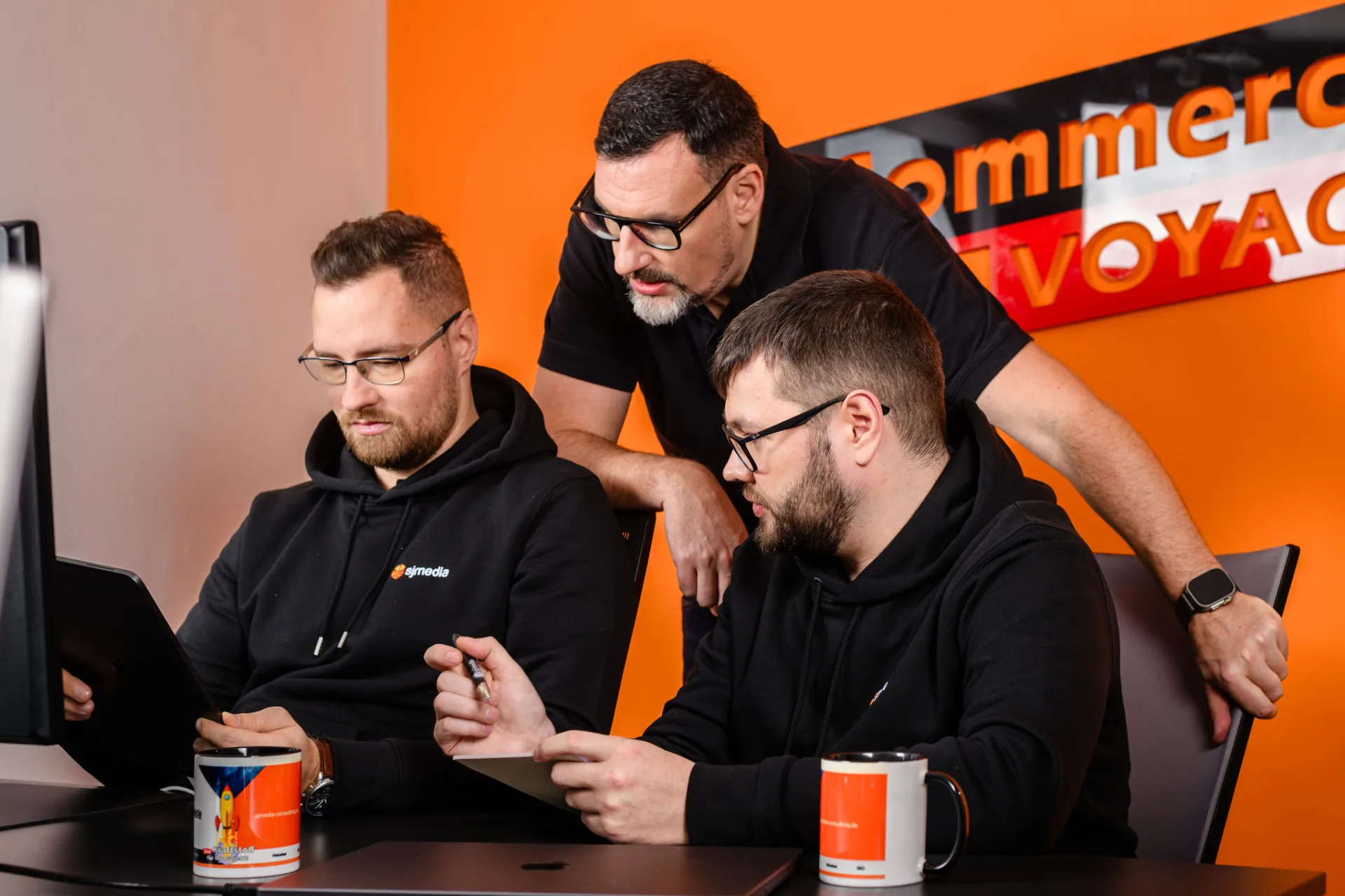 Drei sjmedia-Mitarbeiter besprechen ein E-Commerce-Projekt am Arbeitsplatz