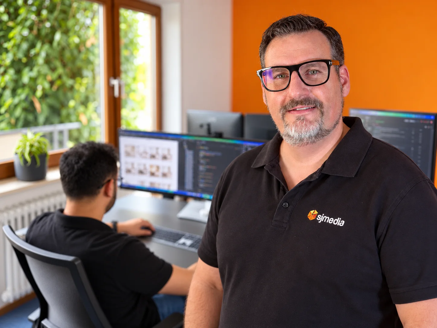 Jochen Schmid welcomes visitors to the sjmedia office while the team works on an online store in the background